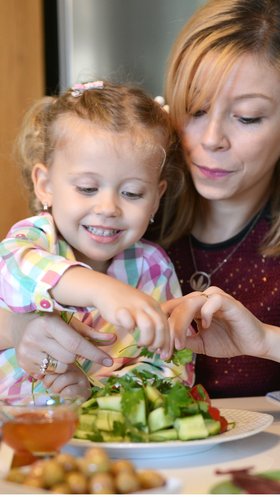 Moeder met kind eet verse salade met verse dadels
